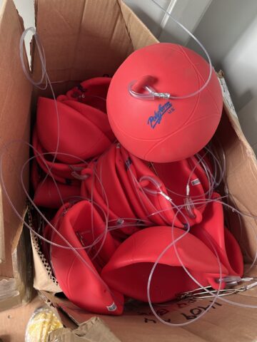 A Box Of Red Buoys, Some Inflated And Other Not Yet.